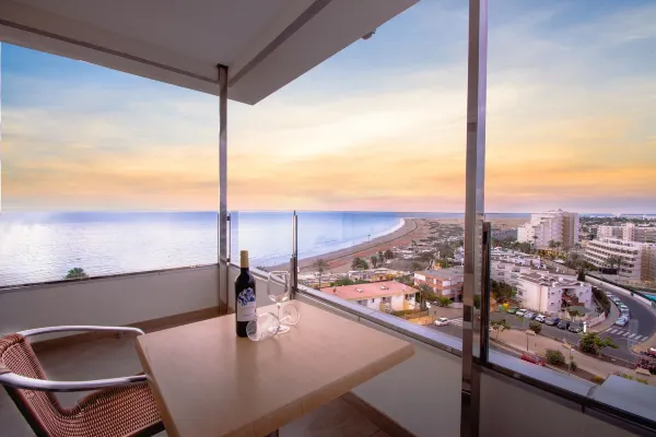 a table with wine glasses and a bottle on it overlooking a beach